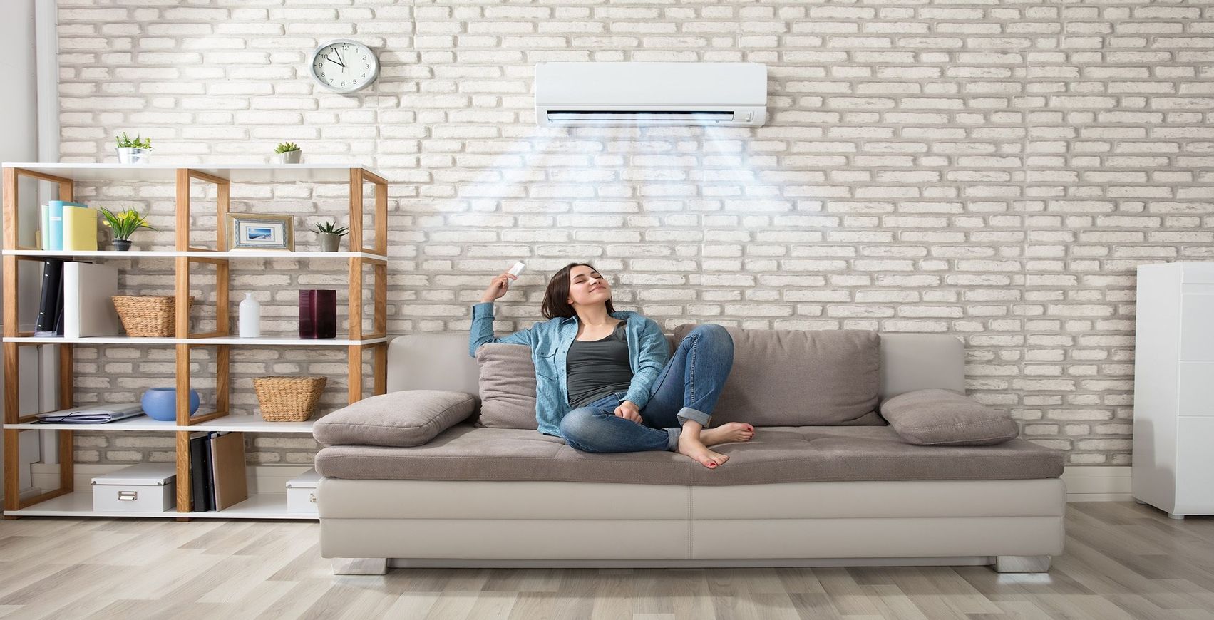 Eine Frau sitzt auf einer Couch und entspannt sich unter einer Klimaanlage